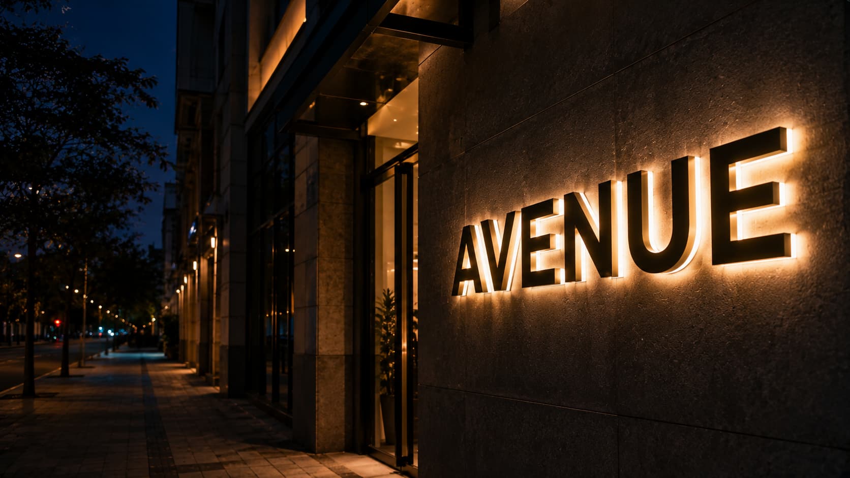 Elegante rótulo luminoso AVENUE con retroiluminación en la fachada nocturna. Fabricación de letras corpóreas y montaje llave en mano en España.