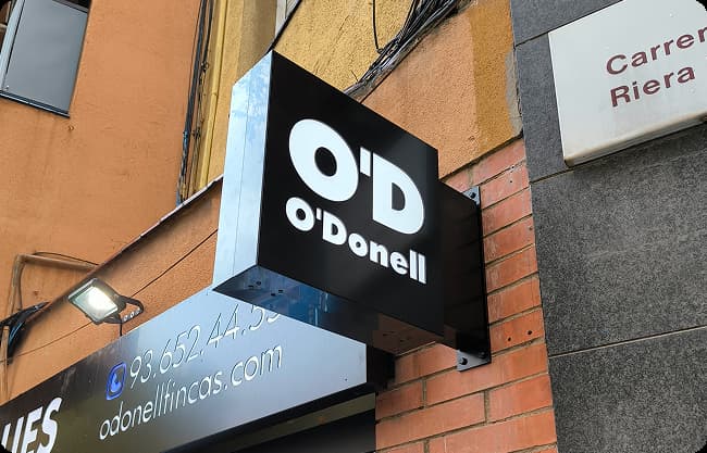 Caja de luz luminosa de doble cara (banderola) O'Donell instalada en la fachada de un edificio
